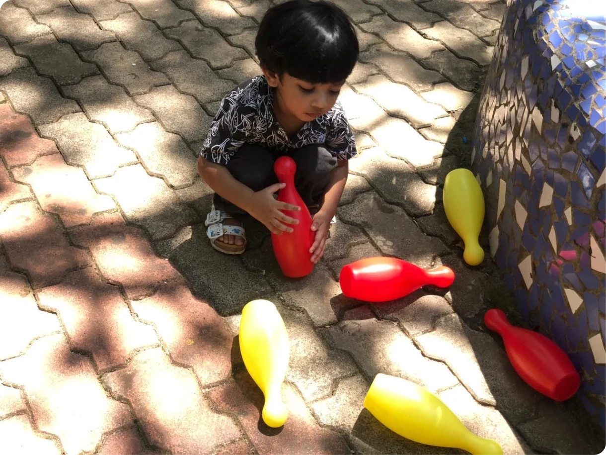 A child playing with skittles in the Shanti Niketan courtyard